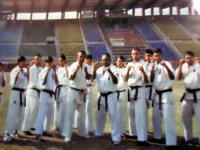 A line of black belts standing in a stadium.